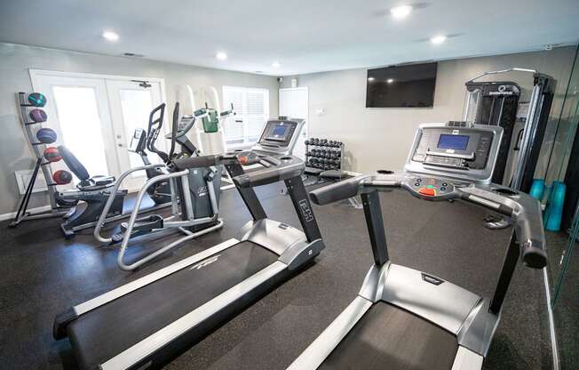 A gym with treadmills, exercise bikes, and other equipment.