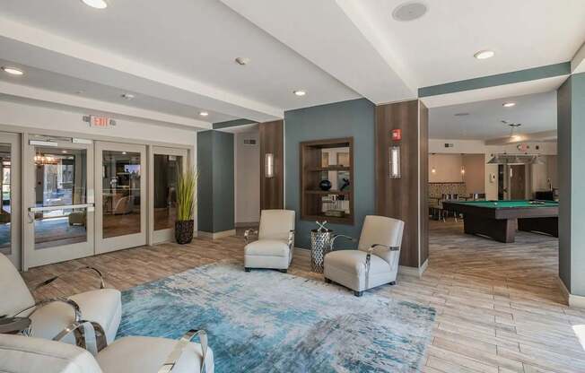 A spacious room with a blue rug and white chairs.