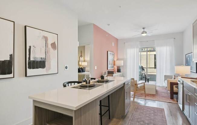 A kitchen with a white countertop and a pink wall.