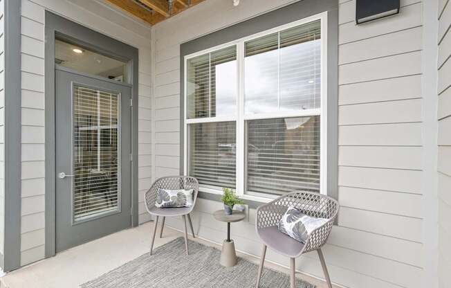 the front porch of a house with two chairs and a table