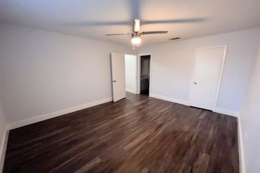 an empty living room with wood flooring and a ceiling fan