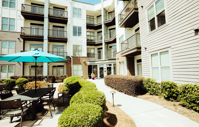 a patio with tables and umbrellas in front of an apartment building