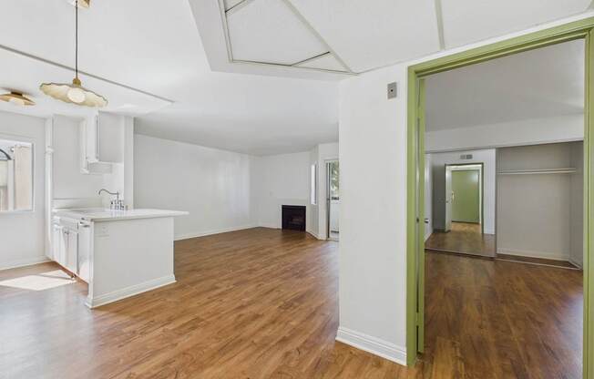 A room with a white kitchen and wooden floors.
