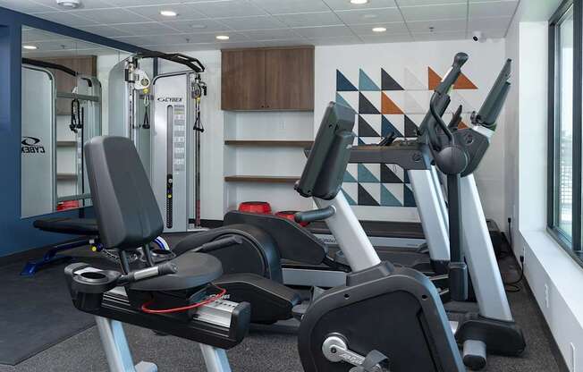 A gym with a row of stationary bikes and a row of treadmills.