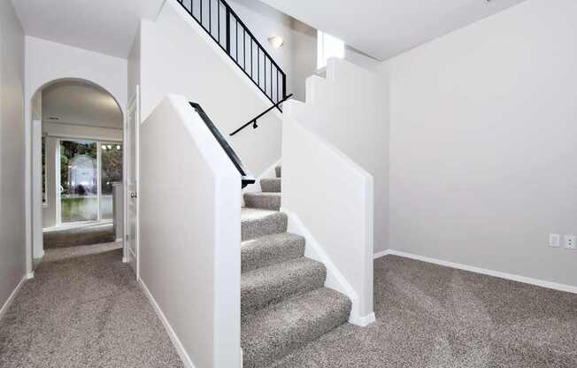 A staircase with a black railing leads to a second floor.