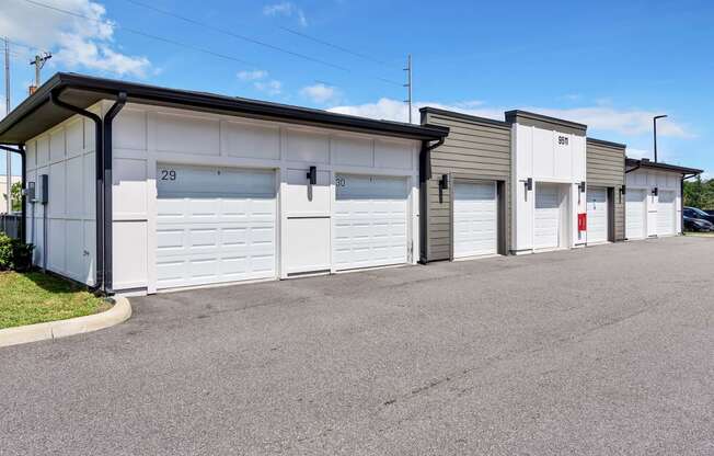 a row of garages with white doors and gray siding