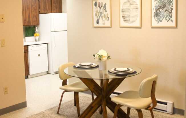 Dining Area that leads into kitchen. Staged with dining table, 2 chairs, wall art and a rug.at The Lakes Apartments, Washington