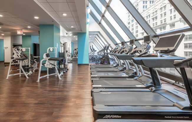 a row of treadmills and elliptical trainers in a gym