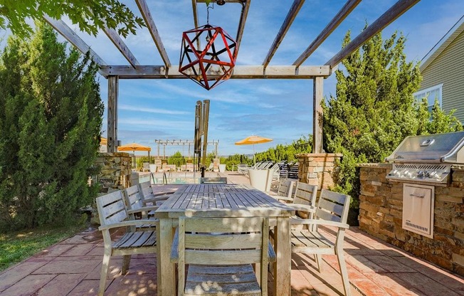 the patio has a dining table and chairs and a grill