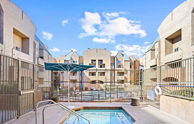 A pool surrounded by buildings and a fence.