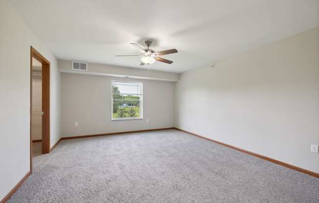 an empty living room with a ceiling fan and a window