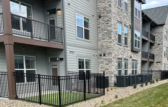 an apartment building with a yard and a black fence at The Depot in Raymore, MO 64083