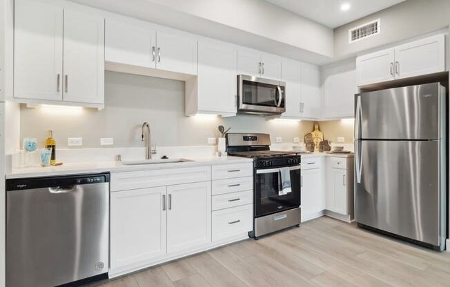 a large kitchen with white cabinets and stainless steel kitchen appliances at Arrive Temecula