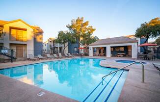 A swimming pool surrounded by a fence and chairs.
