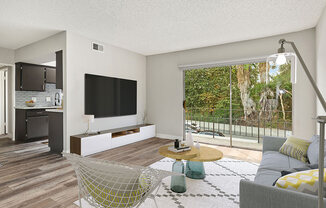 Hardwood floored living room with view of balcony and kitchen.