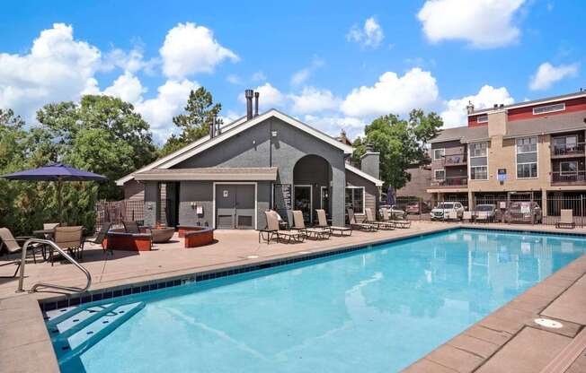 A pool area with a building and chairs.