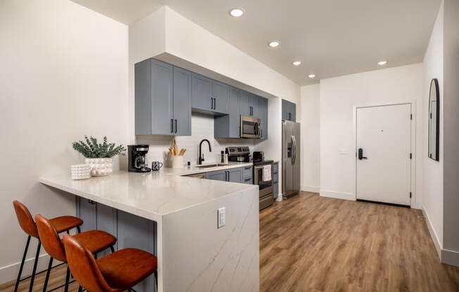A kitchen with a white counter top and brown chairs.