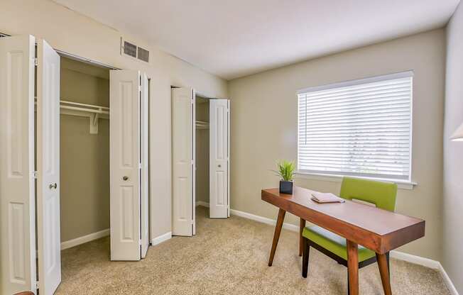 a room with a desk and chair and a closet with a window