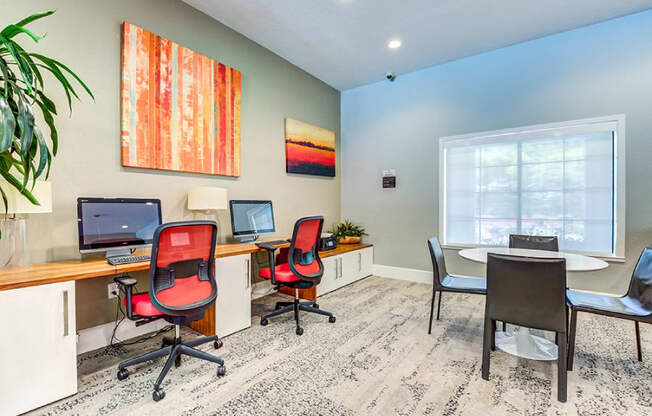 A room with a desk, chairs, and a computer.