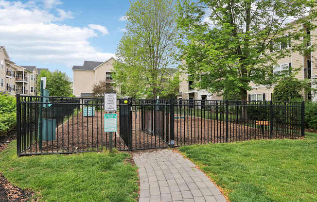 A sign in front of a fence with a pathway leading to a building.
