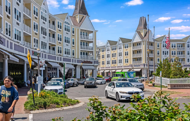 A woman in a blue shirt is walking on a street with a white car parked on the side.