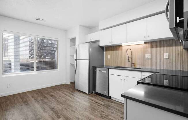 A kitchen with white cabinets and a black countertop.