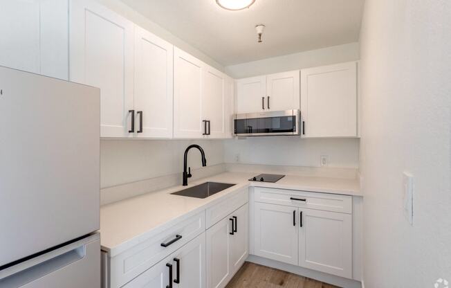 a kitchen with white cabinets and a sink and a refrigerator