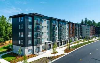 a rendering of a large apartment building with a street in front of it at STATION BY VINTAGE, COVINGTON, WA 98042