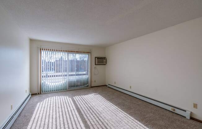 the living room of an apartment with a sliding glass door. Fargo, ND Windsor Apartments