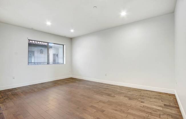 an empty living room with wood flooring and a window