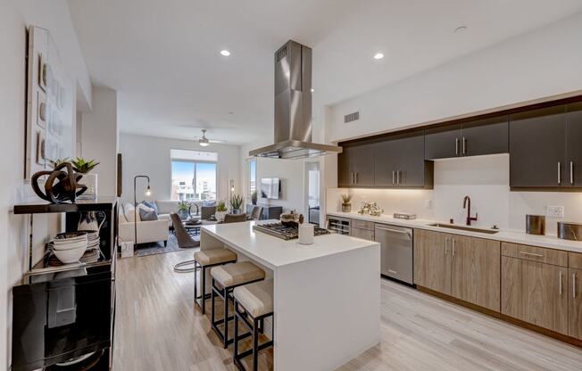 an open kitchen and living room with a large white island with stools