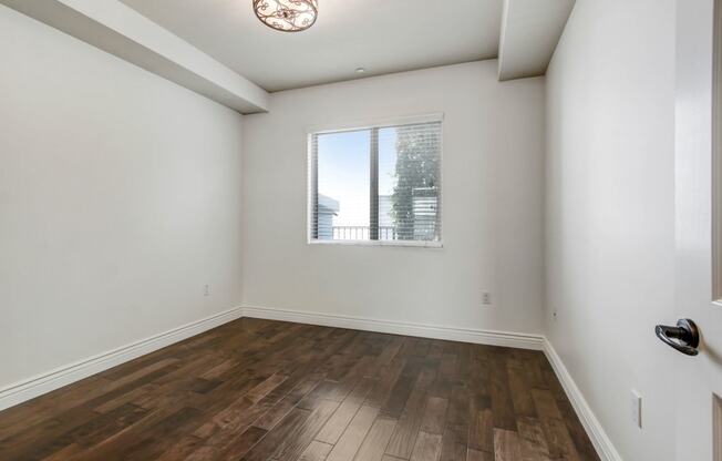 a bedroom with hardwood floors and a large window