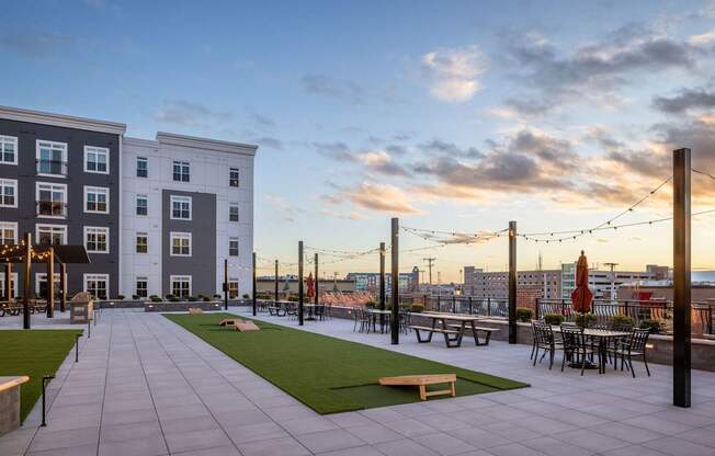 A rooftop patio with tables and chairs overlooks a city skyline.