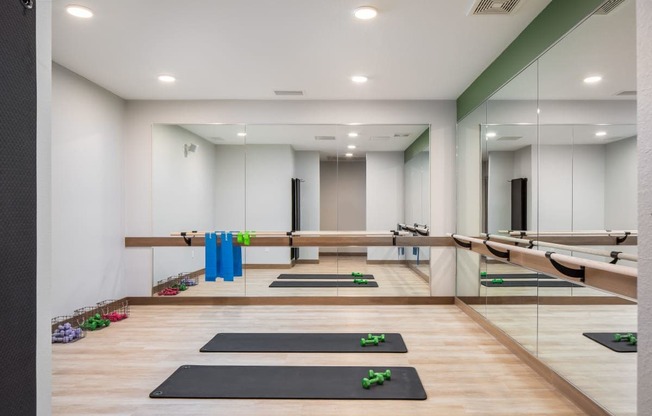 A yoga studio with mats and blocks on the floor.