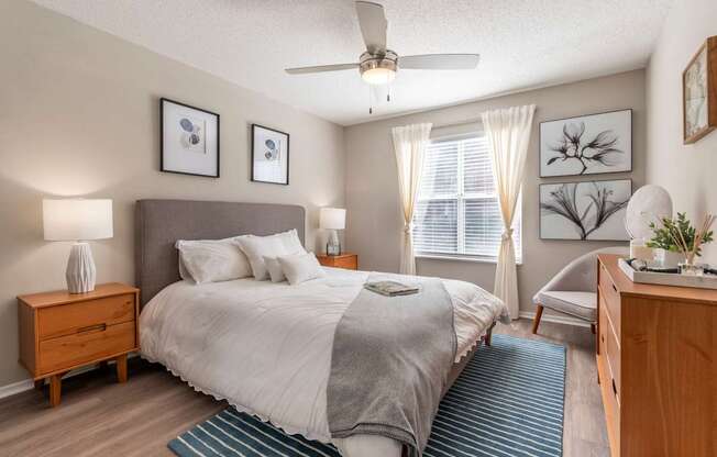 A bedroom with a bed, nightstand, and a ceiling fan.