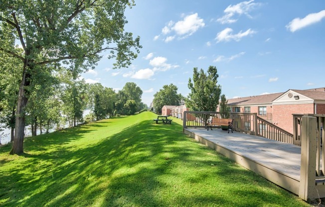 a park with a grassy field next to a building with benches at Brightwaters Apartments, Little Rock, Arkansas