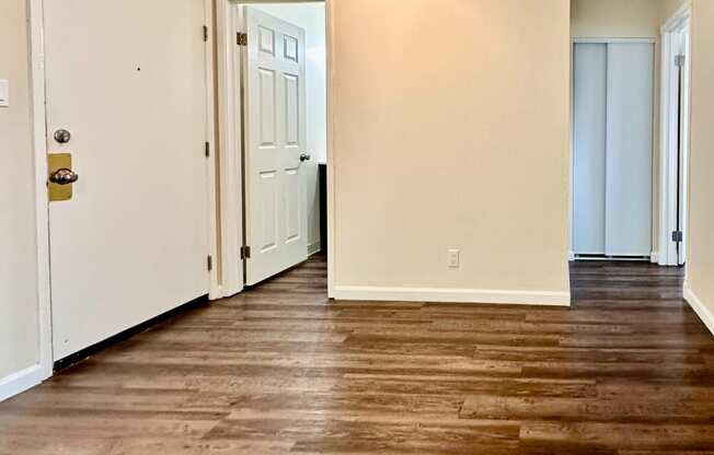 an empty living room with a hard wood floor and white walls