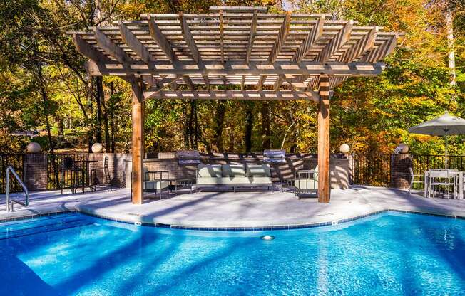 a swimming pool with a wooden pergola next to it
