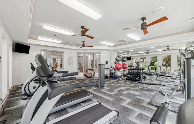 A gym with treadmills, weights, and exercise equipment.