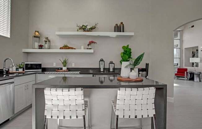 A modern kitchen with a large island and two chairs.