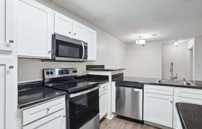 Apartments for Rent in Little Rock, AR 72223– Capitol Hill - A kitchen with white cabinets and black countertops.