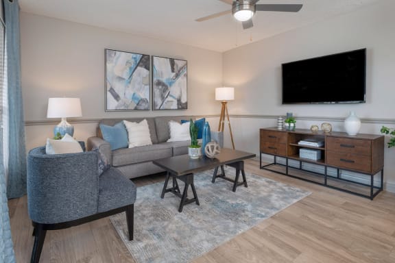 living room with wall mount TV, model furnishings, hardwood-style floor and metallic ceiling fan at Preserve at Cedar River Apartments, Florida, 32210