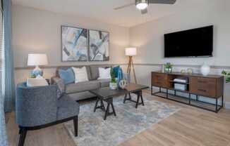 living room with wall mount TV, model furnishings, hardwood-style floor and metallic ceiling fan at Preserve at Cedar River Apartments, Florida, 32210