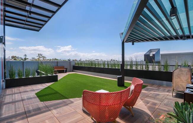 a roof terrace with a lawn and chairs and a pergola