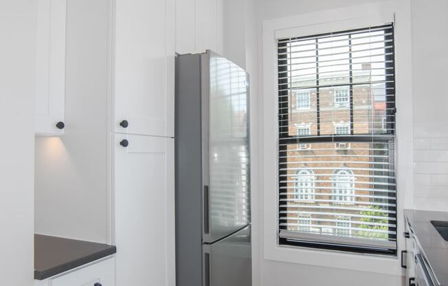 a kitchen with white cabinets and a stainless steel refrigerator