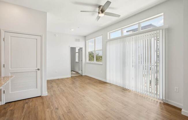 A room with a ceiling fan and a window with blinds.