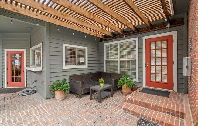 a porch with a couch and a red door