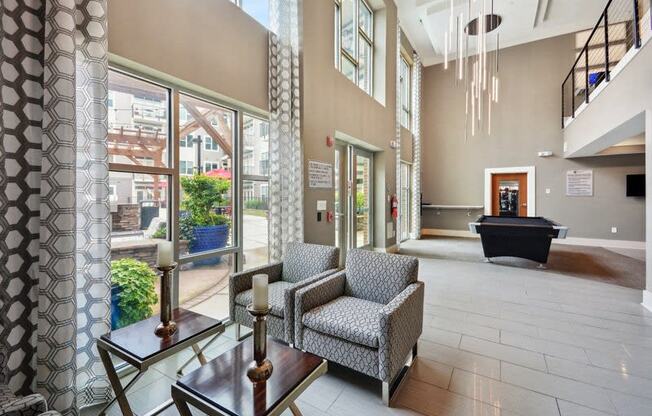 a lobby with chairs and a table in a building with large windows at Link Apartments® Brookstown, Winston Salem, NC, 27101