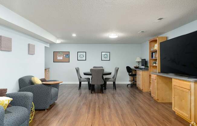 A living room with a grey couch, a black chair, a wooden cabinet, and a television.