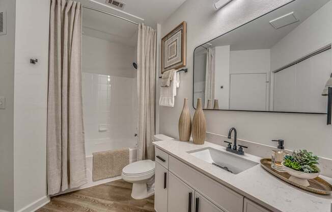 A bathroom with a toilet, sink, and shower.